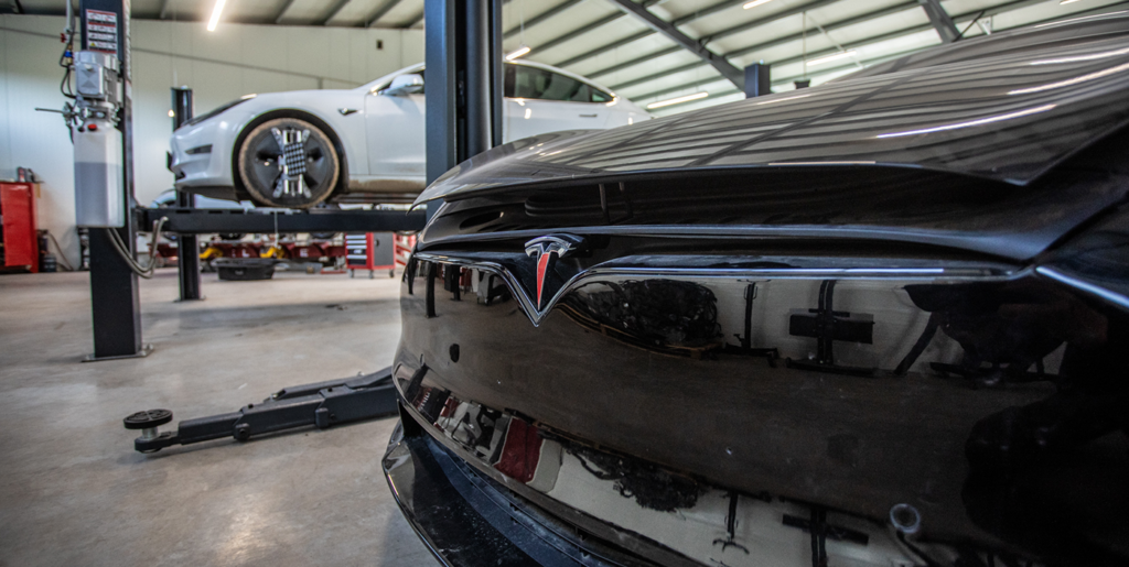 Juodos Tesla priekinė dalis ir automobilis ant keltuvo „TS Vilnius“ servise